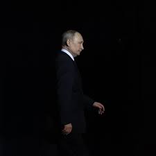 عکسی از ولادیمیر پوتین در حال راه رفتن در مقابل پس زمینه سیاه.